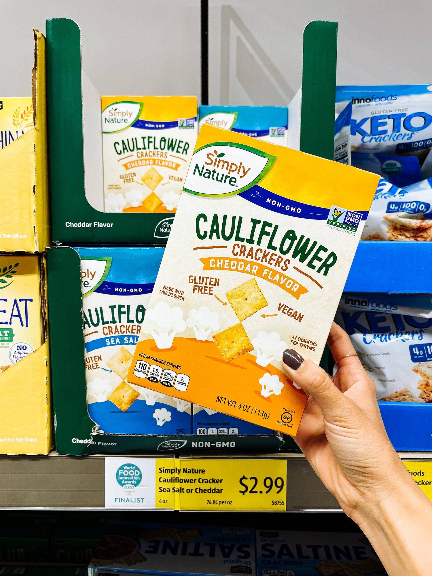 White hand holding cauliflower crackers from ALDI.