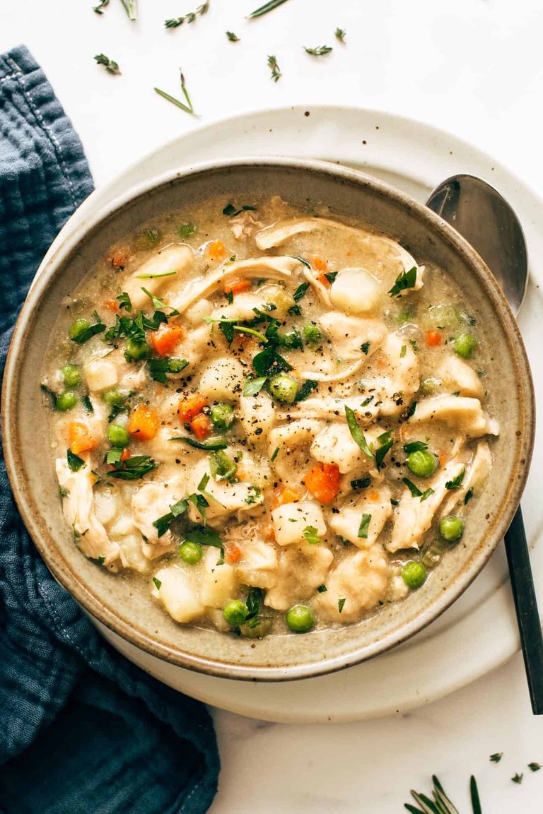 A bowl of chicken and dumplings with veggies in it.