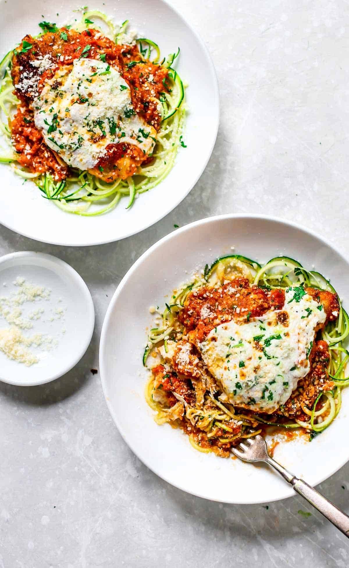 Chicken parmesan on a plate of zucchini noodles.