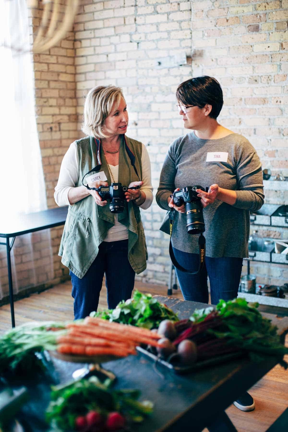 Two women talking while holding cameras.