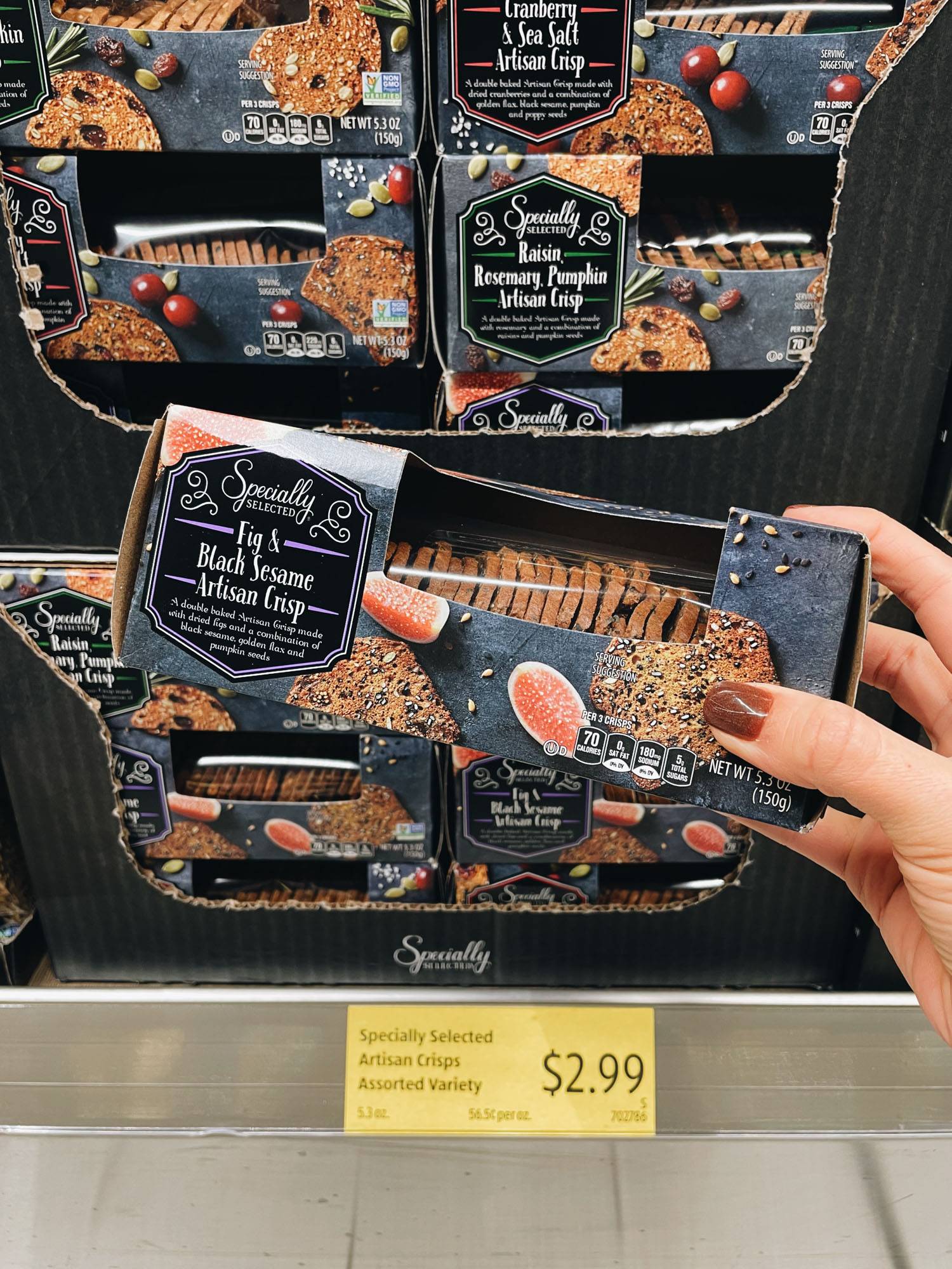 White hand holding box of black sesame crackers