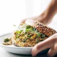 A person placing down a plate with a sandwich on it.