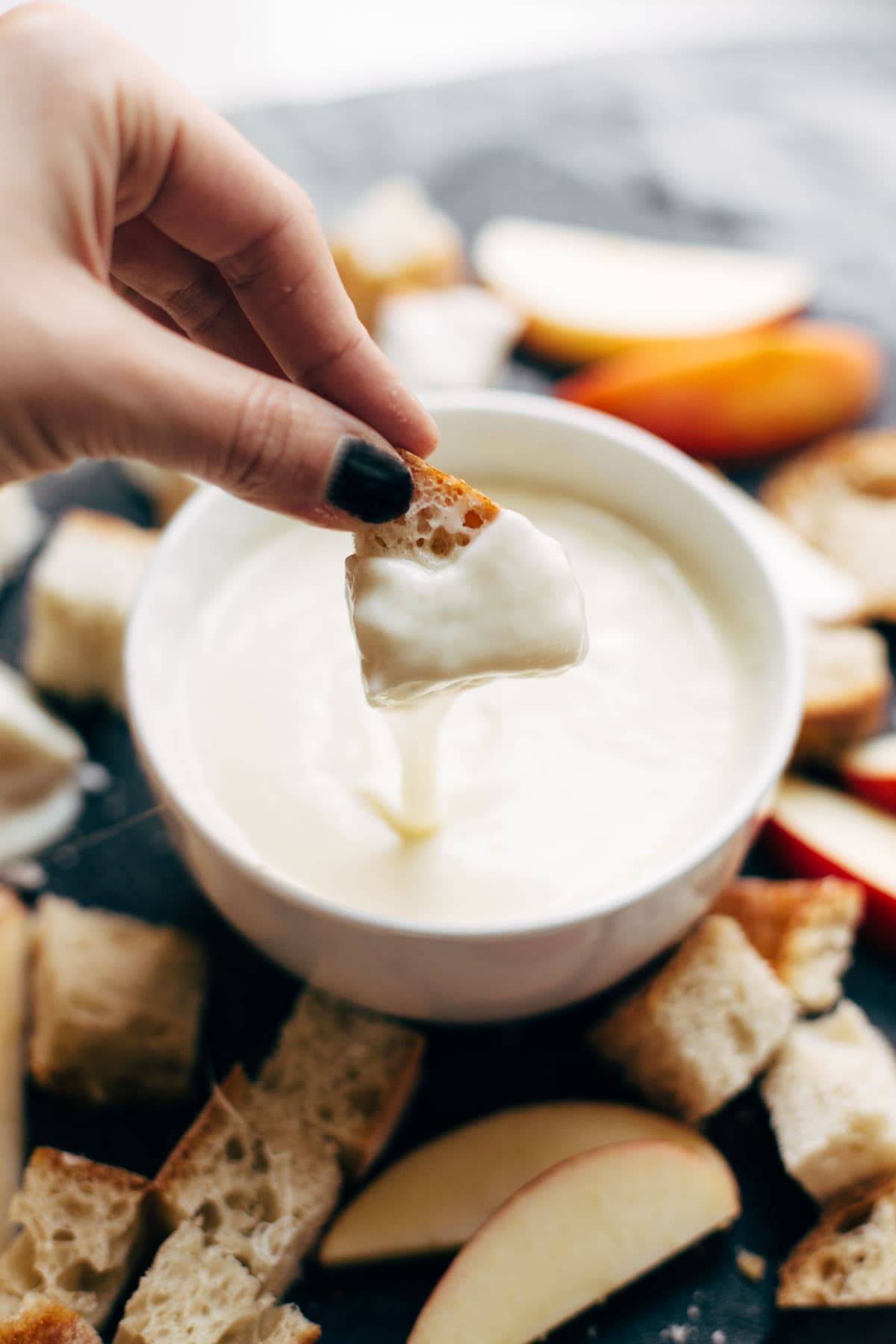 Hand dipping bread in Cheese Fondue