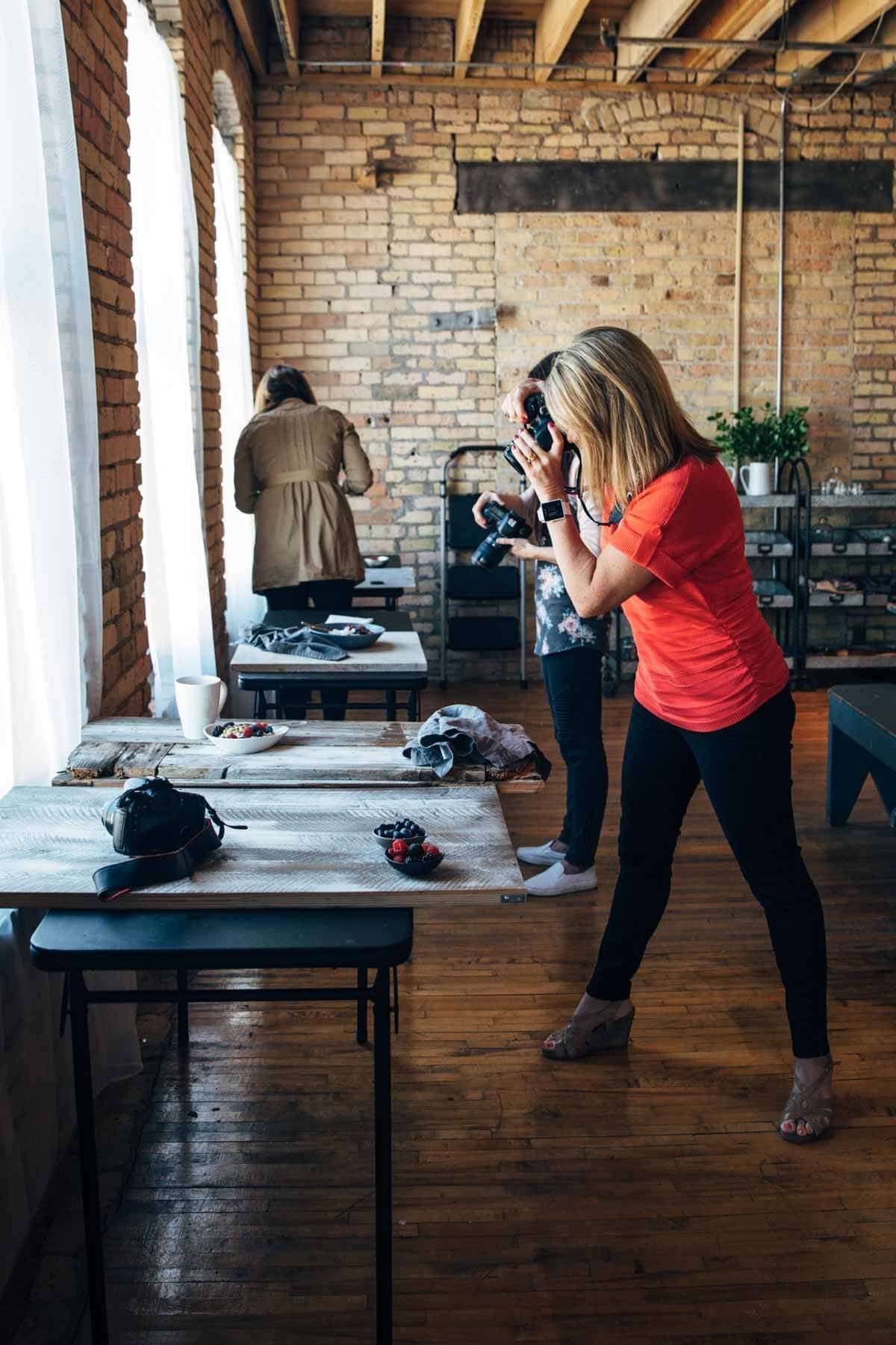 Woman with a camera taking a photo of food on a plate.